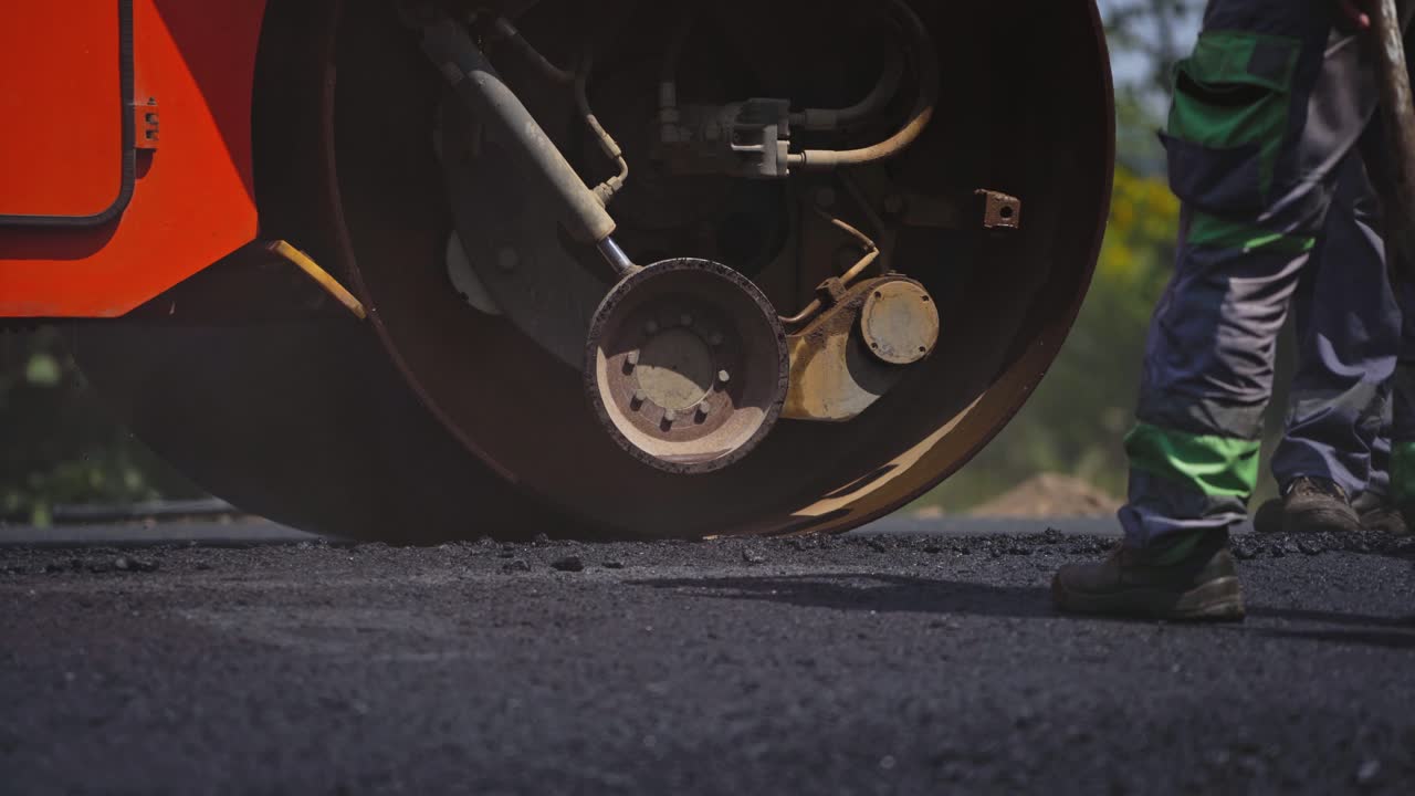 Asphalting of road with steamroller. Roller rolling fresh hot asphalt on the new road