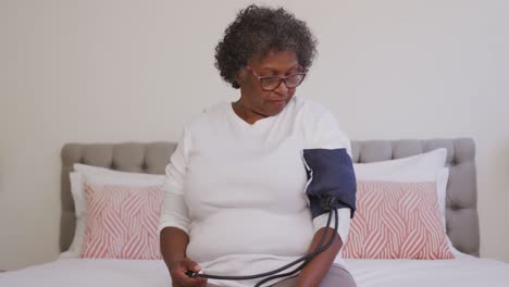 mixed race woman checking her blood pressure. social distancing and self isolation in quarantine