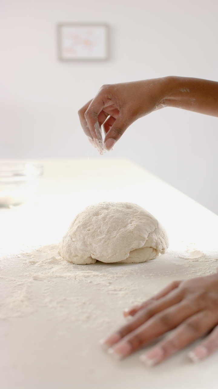 Video verticale: Donna che cosparge farina sull'impasto, prepara pane fatto in casa in cucina