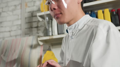 close-up of inventor using tablet in mechanical workshop, background features engine oil containers, shelves, and tools, suggesting research, innovation, and technical evaluation