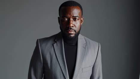 professional businessman standing confidently in gray suit and black turtleneck, posing against neutral gray studio backdrop, radiating corporate elegance