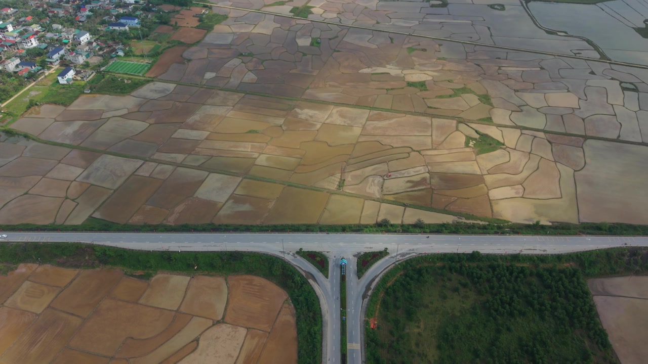 ภาพถ่ายทางอากาศของพื้นที่เกษตรกรรม ภาพถ่ายโดรนทางอากาศที่แสดงนาข้าวและถนนชนบท อากาศยานไร้คนขับบันทึกภาพมุมกว้างของพื้นที่เพาะปลูกและเส้นทางคมนาคม