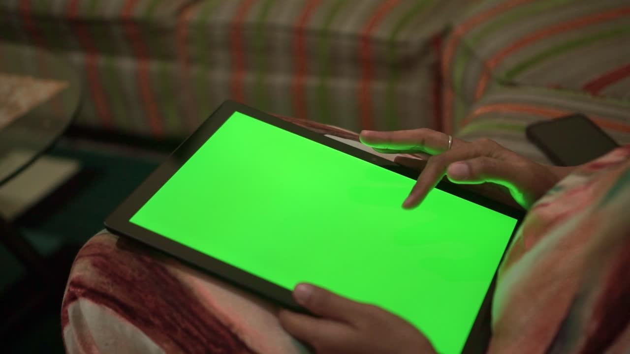 Hand using tablet green screen at home. Online content, app demo, and digital lifestyle