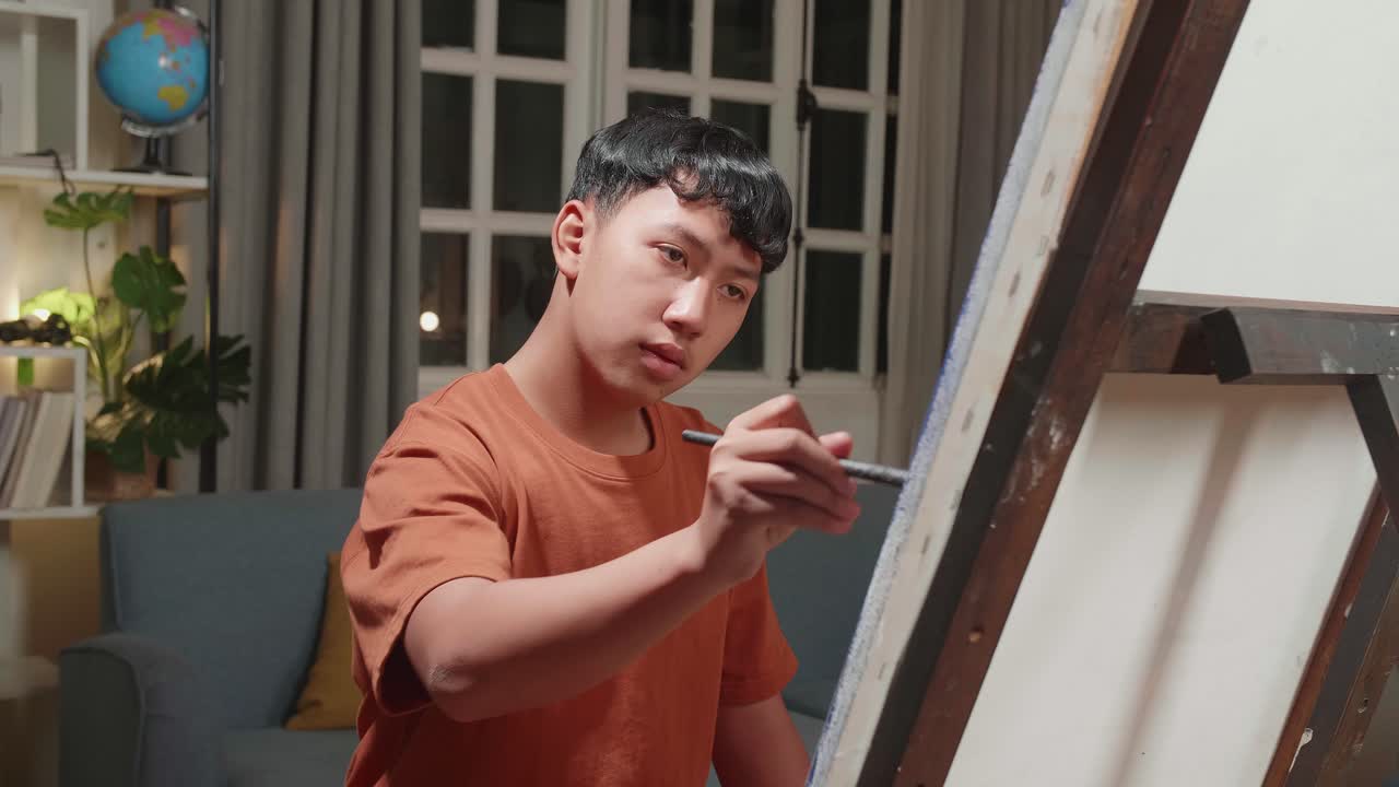 Medium Close Up Of An Asian Artist Boy Holding Paintbrush Mixed Colour And Painting On The Canvas