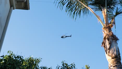 a police helicopter circling a house in la with a blue sky