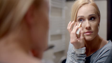 pretty blond woman applying eyebrow makeup