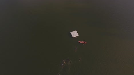 aerial view of kids swimming to a lake's platform in a summer camp