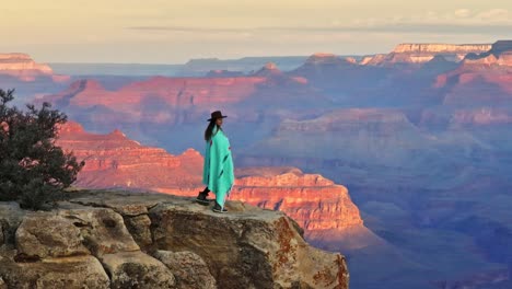 Mujer-Parada-En-El-Borde-Del-Acantilado-Mirando-El-Paisaje-Escénico-Del-Parque-Nacional-Del-Gran-Cañón-En-Arizona,-EE.UU.---Disparo-De-Drone