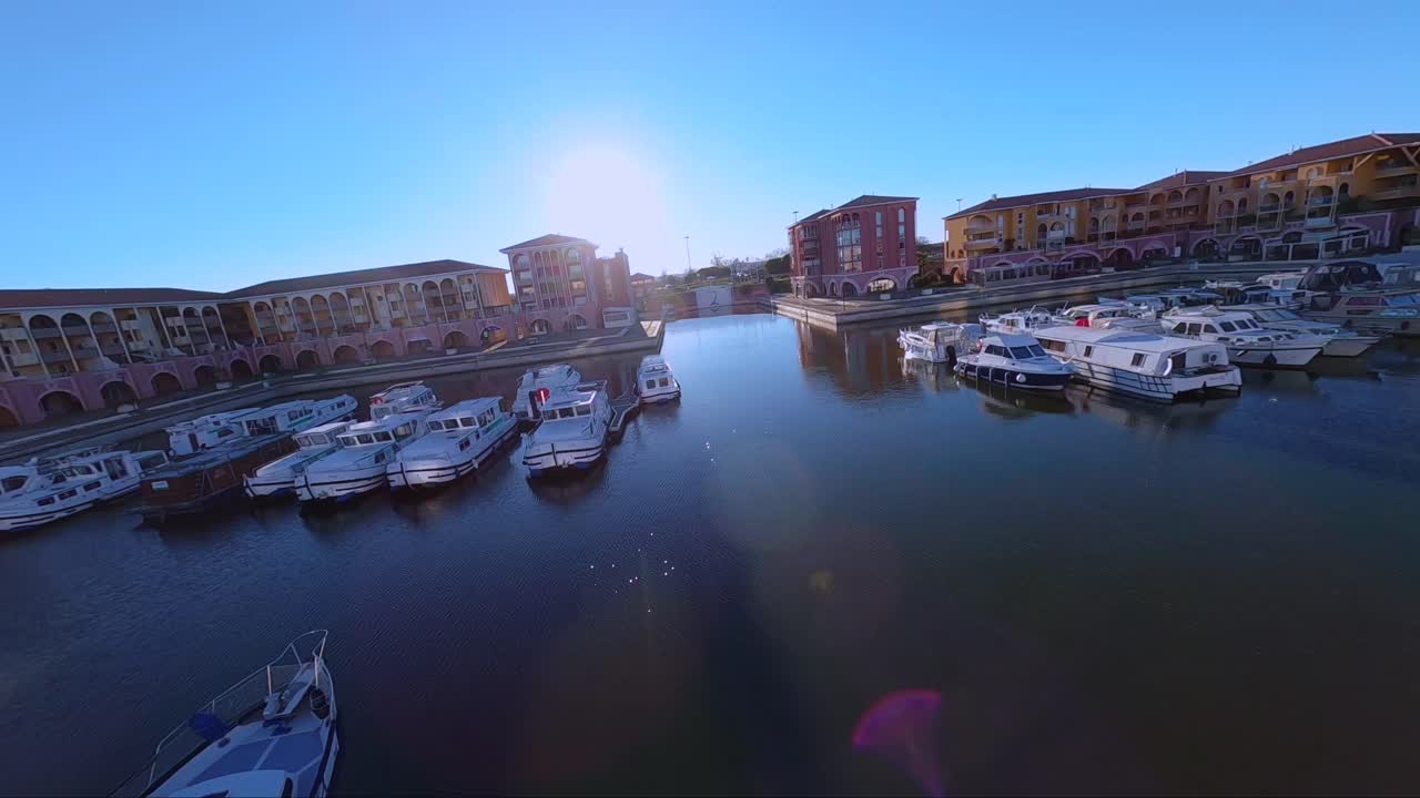 화려한 건물 옆에 정박한 보트와 함께 포트 아리안을 드러내는 시네마틱 fpv 다이빙 샷