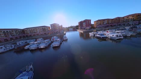 Cinematic-FPV-diving-shot-revealing-Port-Ariane-with-boats-docked-beside-colourful-buildings