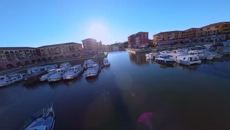 cinematic fpv diving shot revealing port ariane with boats docked beside colourful buildings