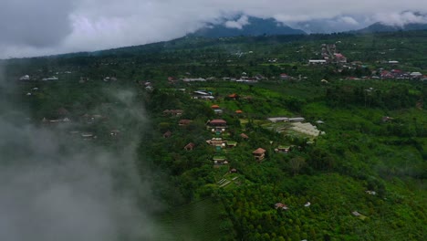 aerial-of-mountain-hotel-resort-through-the-fog-and-rain-clouds-in-Munduk,-Bali,-Indonesia