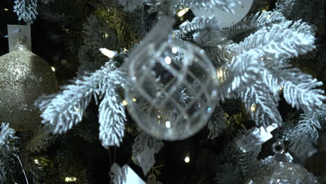 Closeup-dolly-shot-of-Christmas-bauble-hanging-on-a-large-Christmas-tree,-with-fairy-lights