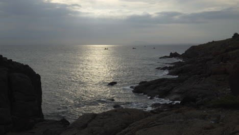 Wunderschöne-Aussicht-Auf-Den-Sonnenuntergang-Von-Einem-Felsigen-Strand-Auf-Der-Halbinsel-Muine,-Vietnam,-Mit-Einem-Kleinen-Boot-In-Einiger-Entfernung