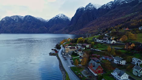 descending drone flight over a lakeside village in a valley surrounded by snow-capped mountains