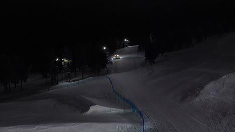 Aerial-of-snow-machine-at-work-in-Idre,-Sweden-during-a-late-evening-in-the-dark-7