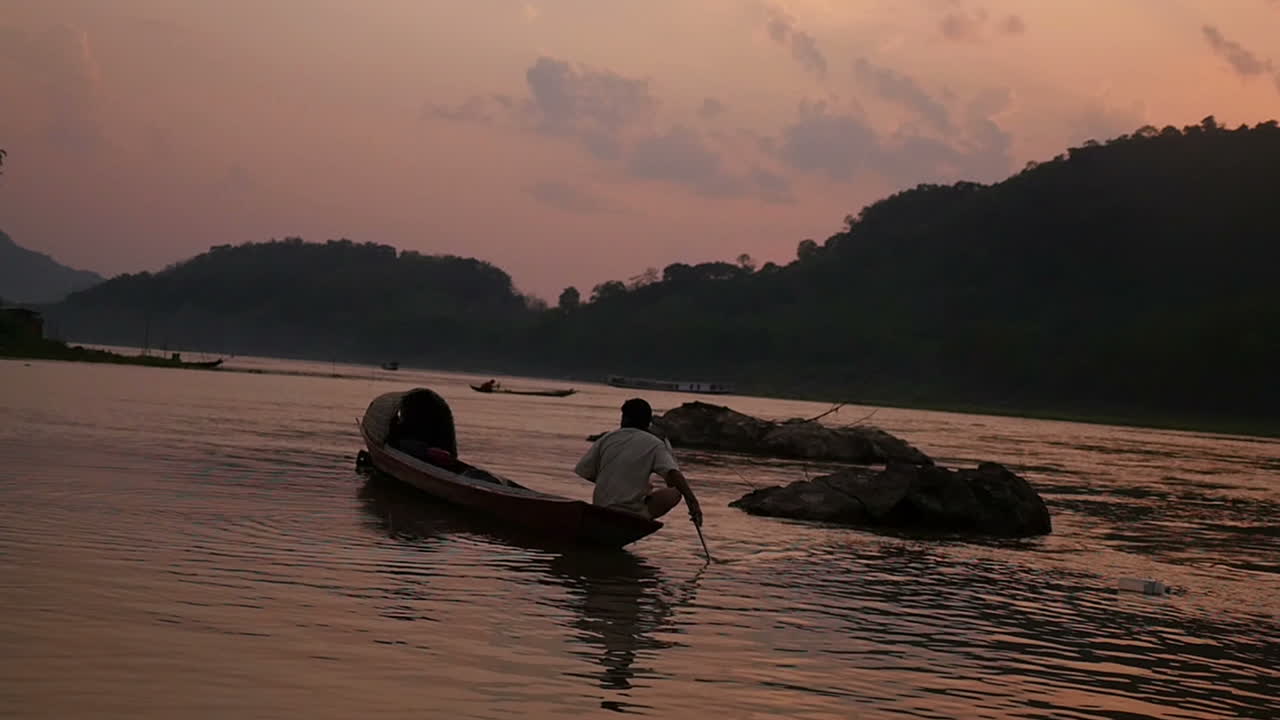 Man in a traditional boat on a river at sunset