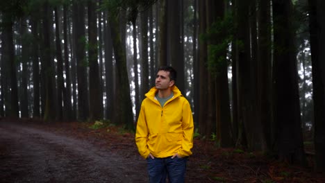 medium shot of man in yellow raincoat waiting in dark, scary forest