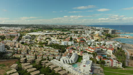 Panoramic-aerial-view-of-Pernera,-Cyprus,-showcasing-the-dense-residential-area,-tourist-accommodations,-and-the-vast-Mediterranean-Sea-in-the-backdrop