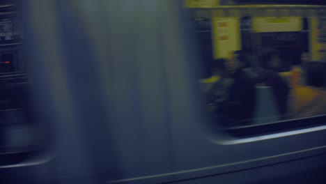 fast-forward-moving-train-metro-view-exterior-look-into-the-interior-of-the-vehicle-with-passengers-sitting-and-standing-walking-out-in-open-space-with-city-building-in-the-background