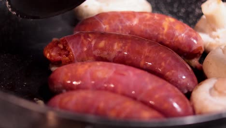 sausages and mushrooms being cooked in a pan