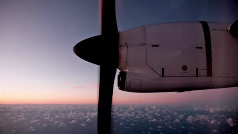 hélice de un pequeño avión que gira a gran altitud sobre el océano y las nubes al crepúsculo