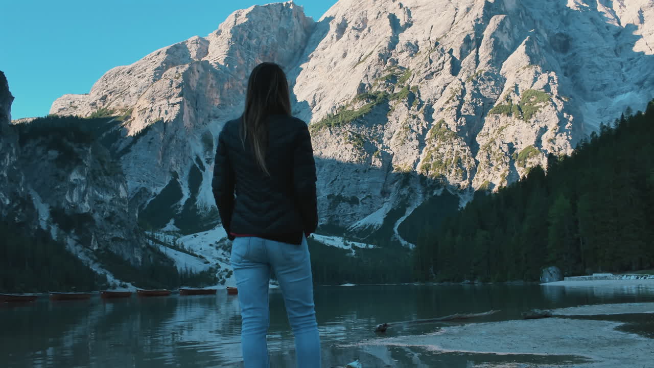 Woman from behind admiring the breathtaking alpine landscape of Lake Braies in the Dolomites