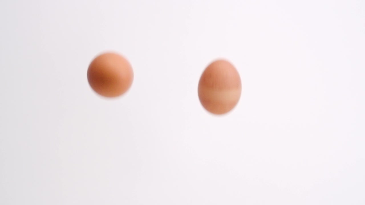 Brown eggs falling in slow motion on white studio backdrop in 4k