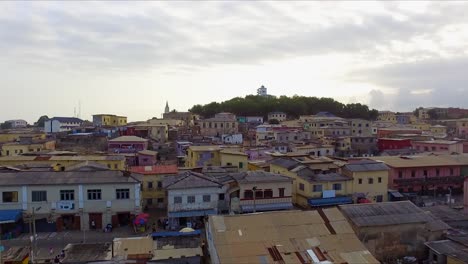 Vista-Aérea-De-Drones-4k-De-Una-Ciudad-Antigua-Con-Casas-Coloridas-En-La-Costa-Del-Cabo,-Ghana,-África