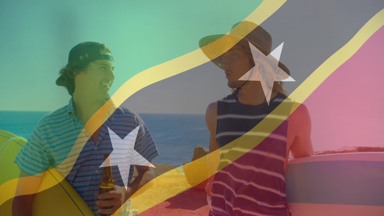 Talking on beach, two men with surfboards over Saint Kitts and Nevis flag