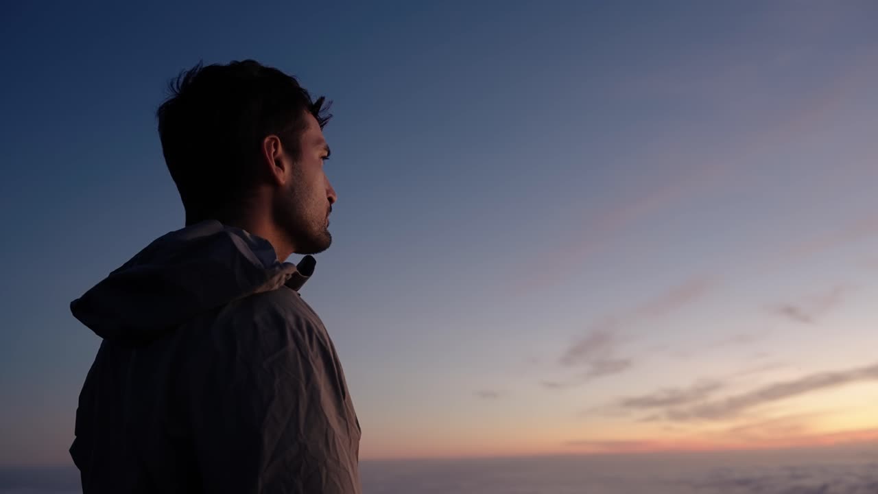 Side profile of a man looking toward the colorful sky during sunset at Pico do Arieiro, Madeira, Portugal.