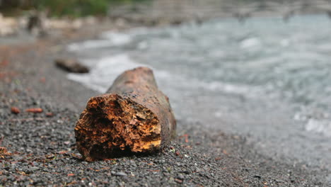 A-Tree-Log-At-The-Lakeshore-In-Lake-Crescent-In-Washington-With-Waves-Splashing---Closeup-Shot