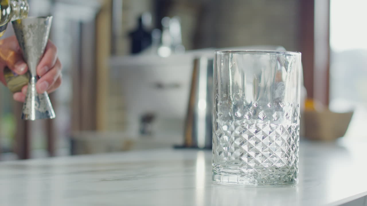 Alcoholic beverage being poured into a glass on a white bar in an elegant bar
