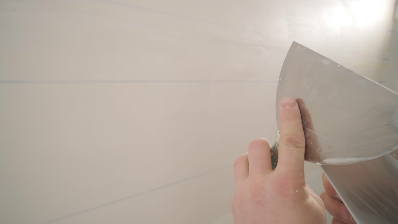 Man plastering the walls with finishing putty in room with putty spatula
