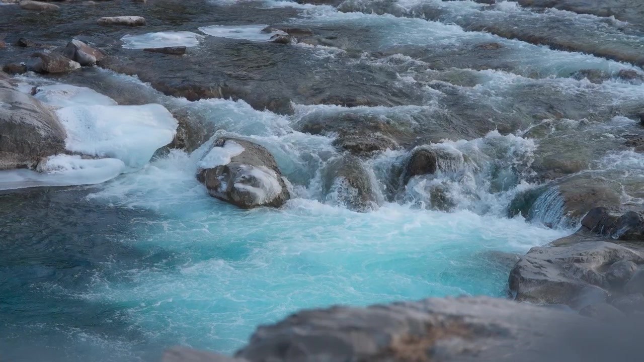 Piccola cascata di acqua blu che scorre tra i massi