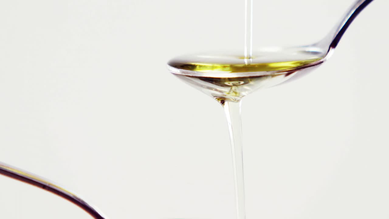 Olive oil being poured on two spoons