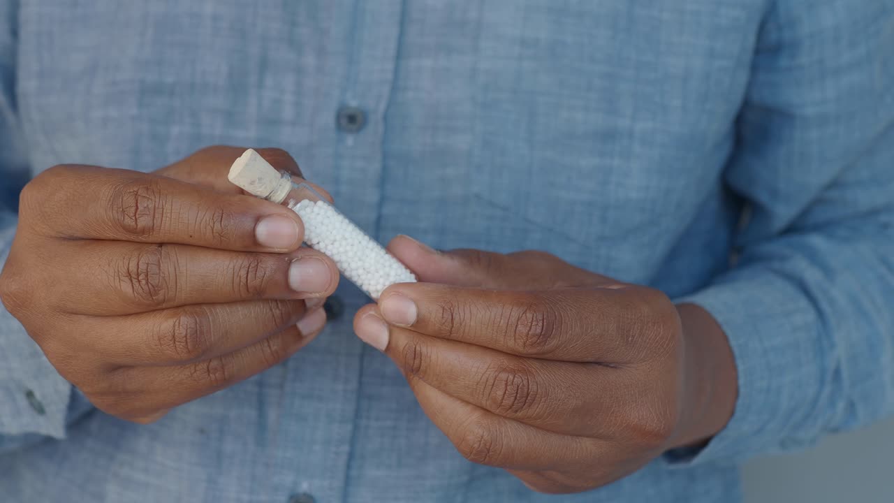Persona che tiene in mano un piccolo flacone di pillole bianche