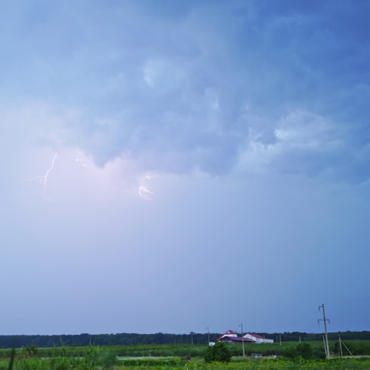 Real flashes of lightning on the blue sky background. The blue sky changes its color into orange after the bright lightning.