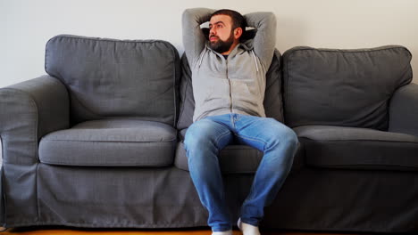 tired caucasian man yawning while sitting in a couch at home