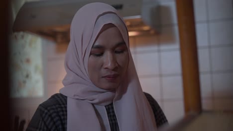 closeup of muslim asian indonesian woman in hijab worried while working in kitchen