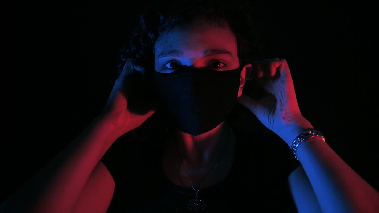 Giovane donna che indossa una mascherina protettiva con illuminazione al neon.