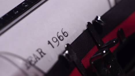 year 1966, typing in vintage typewriter on white paper, close up