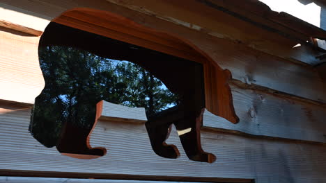 una ventana es la silueta de un oso, marco de madera, cabaña de bosque francés