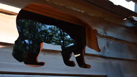 a window is the silhouette of a bear, wooden frame, french forest cabin