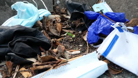 Dirty-disposable-corona-virus-face-masks-and-latex-gloves-among-cigarette-rubbish-on-street-curb-close-pull-back