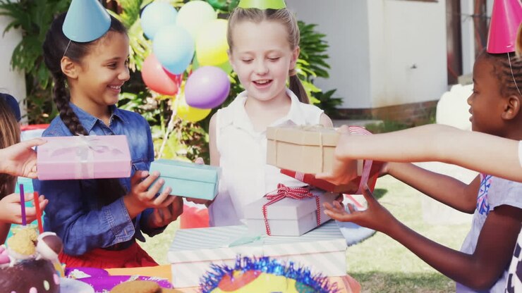Animation of red specks over birthday presents and children having fun at party