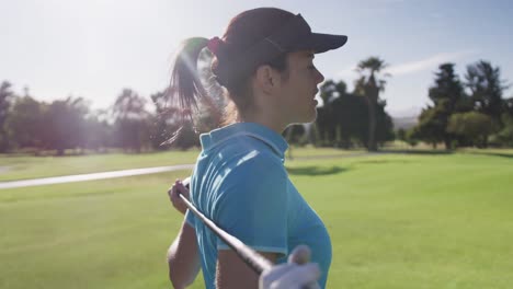 Portrait-of-female-caucasian-golf-player-standing-with-golf-club-around-her-back-at-golf-course