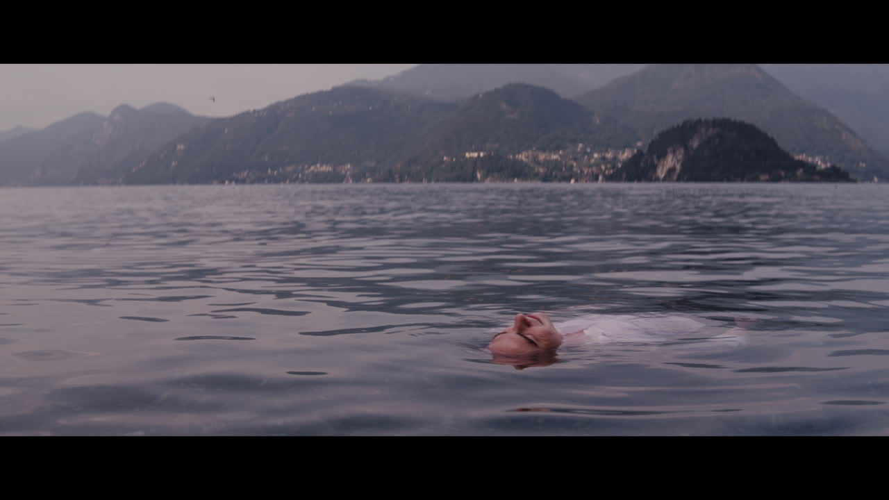 Person floating on a lake in front of mountains