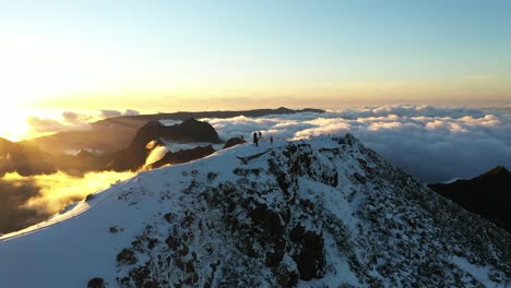 toma aérea de un grupo de personas de pie en la cima de una montaña en madeira