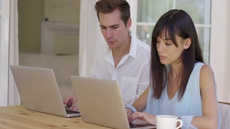 hombre y mujer trabajando juntos en computadoras portátiles